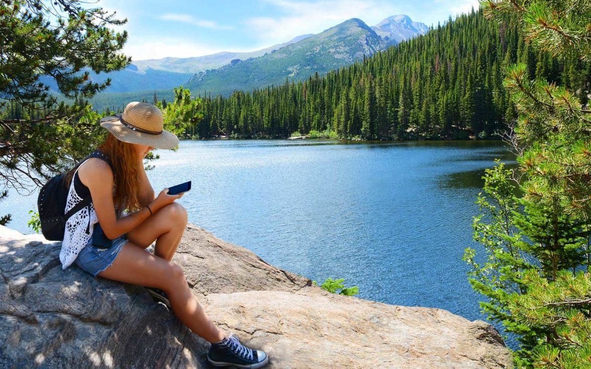 Girl sitting and relaxing on top of mountain rock. 5 Apps to Help You Save Money on Your Next Trip